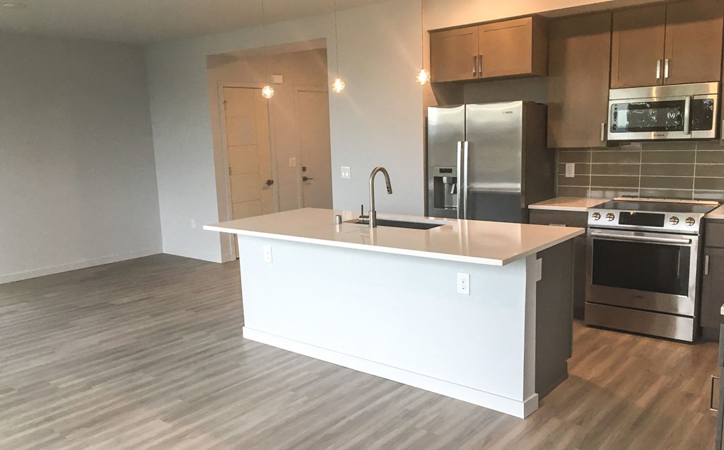 an empty kitchen with an island and stainless steel appliances