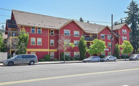 A red building with a grey van parked in front.