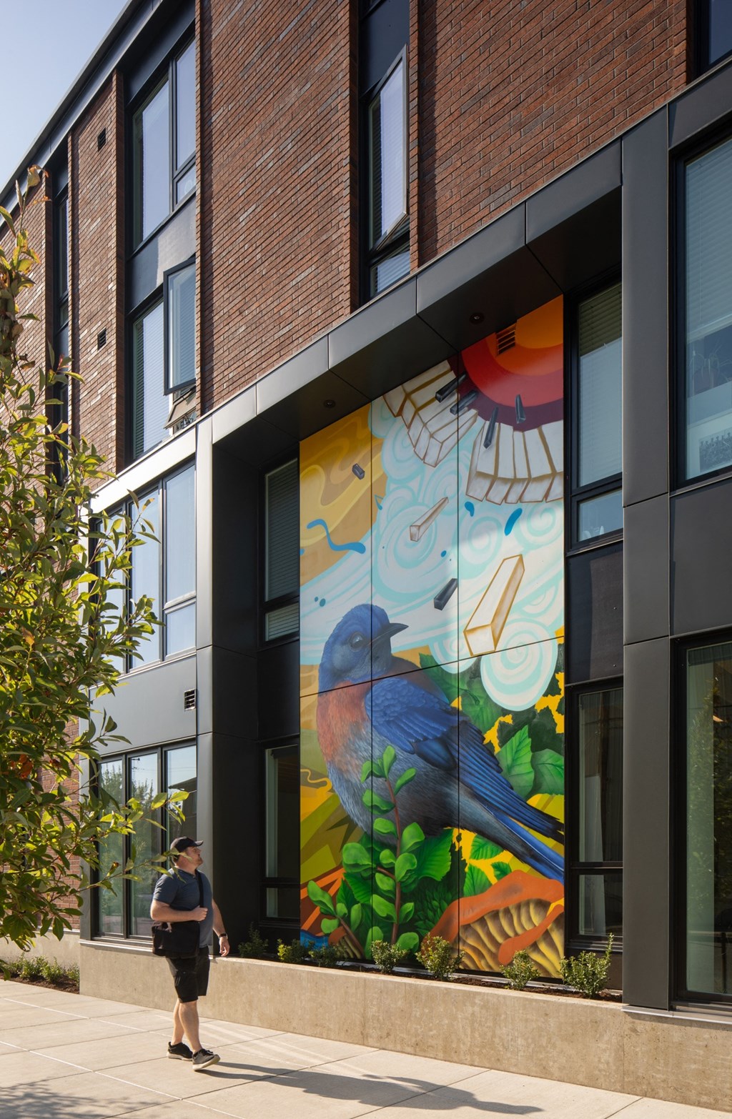 a man walking in front of a building with a mural of a bird