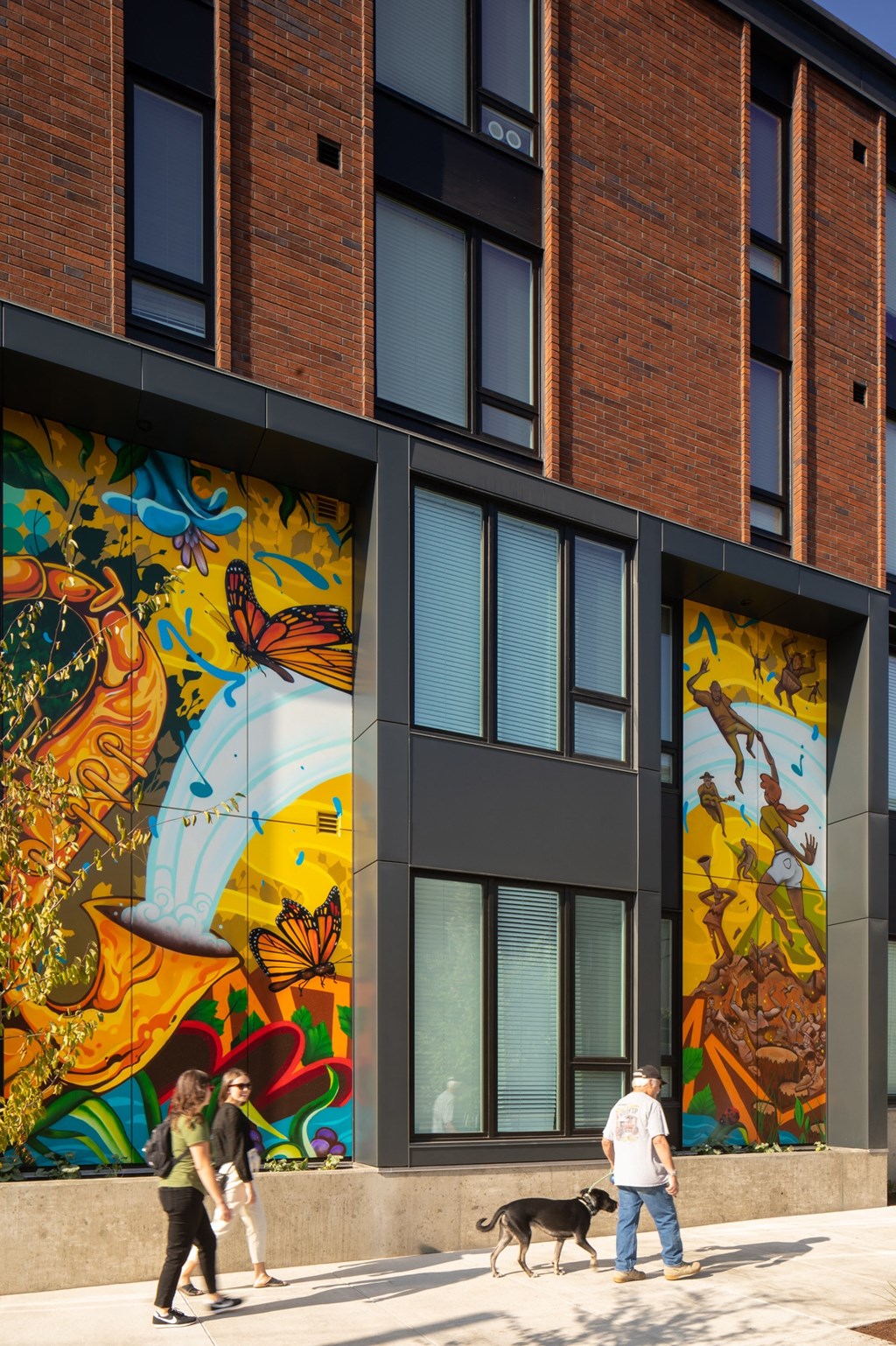 people walking on the sidewalk in front of a building with a mural