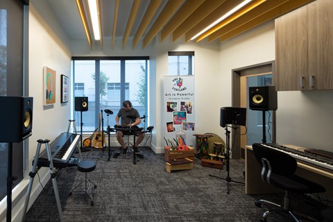 a man playing a guitar in a room with musical equipment