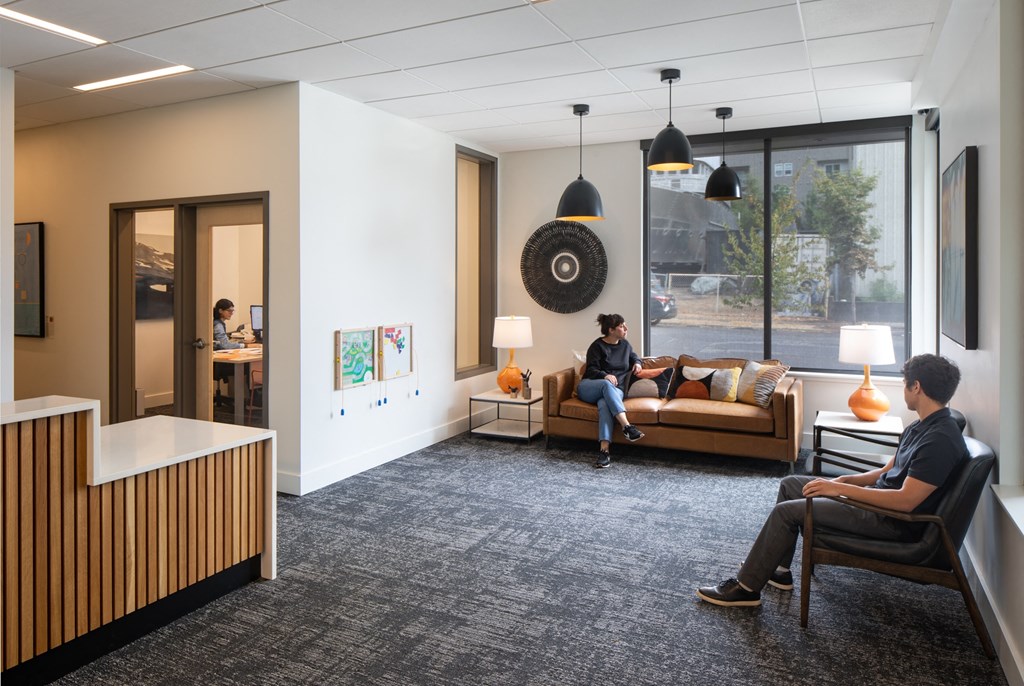 a lobby with people sitting on couches and chairs and a reception desk