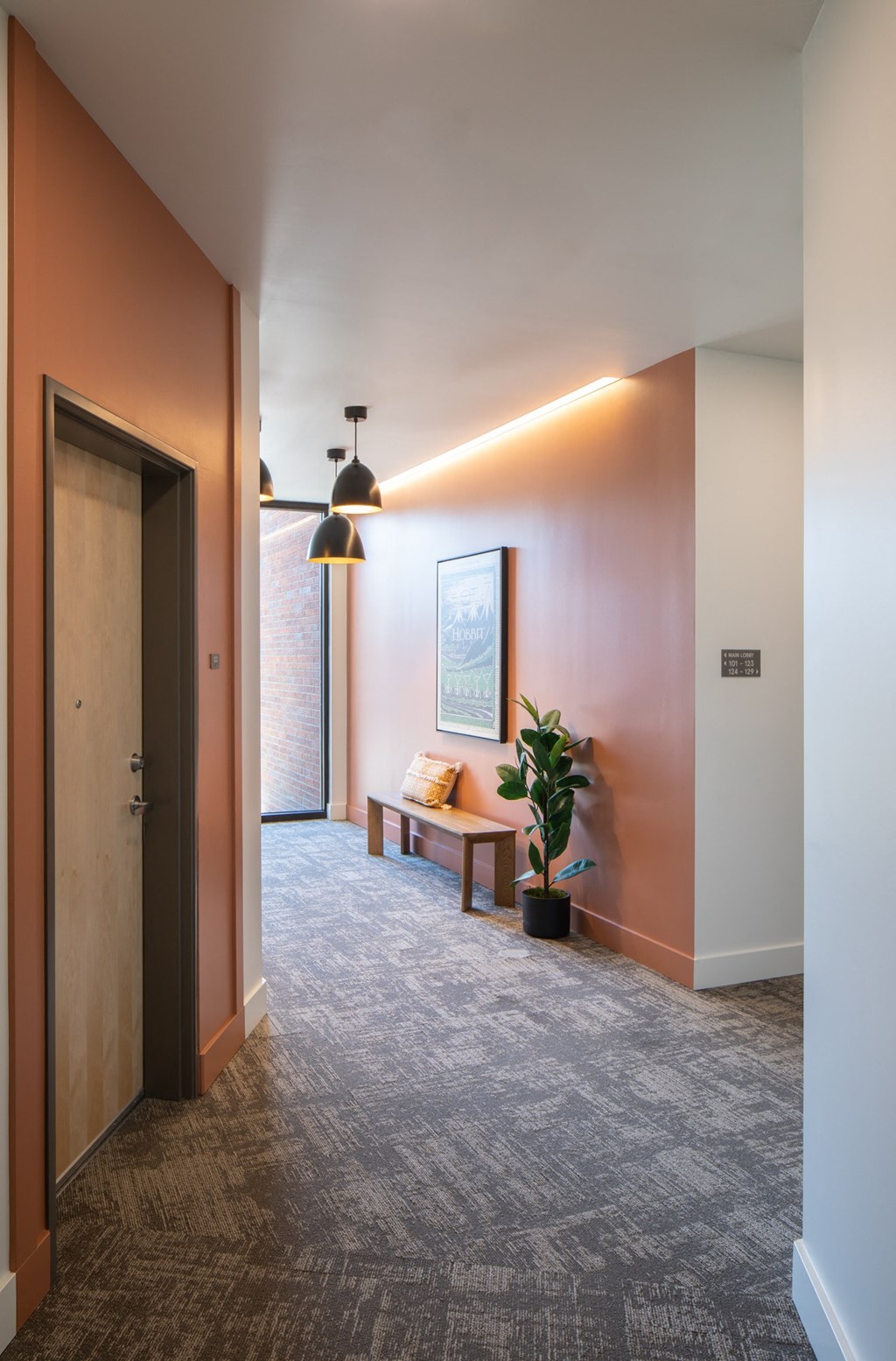 a corridor with a couch and a potted plant in a room with a door