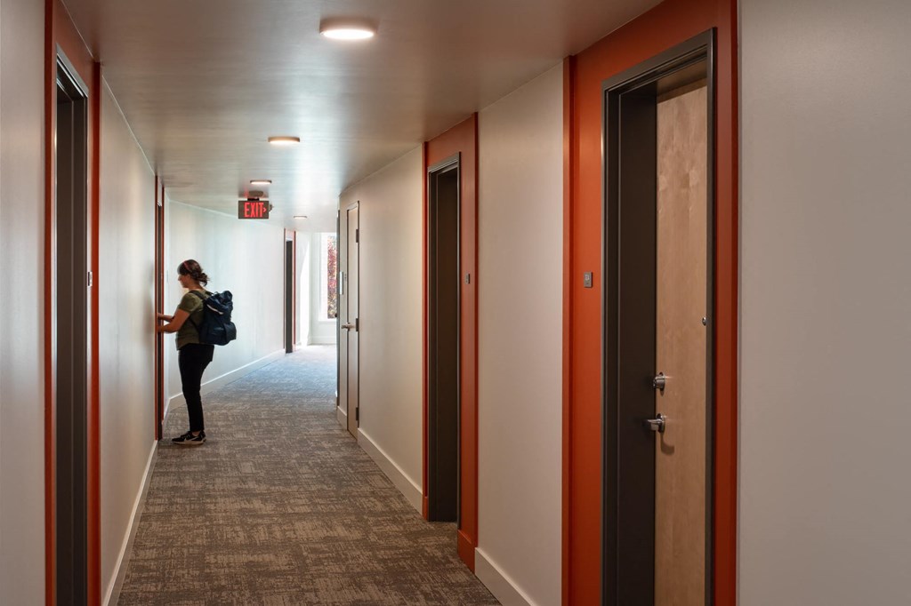 a woman standing in a corridor in a building with closed doors