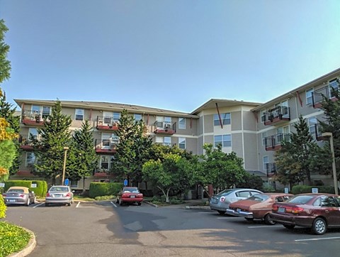 A parking lot in front of a building with cars parked.