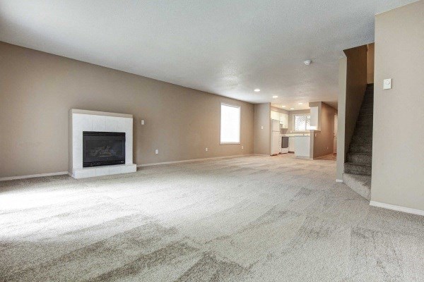 an empty living room with a fireplace and carpeted floors