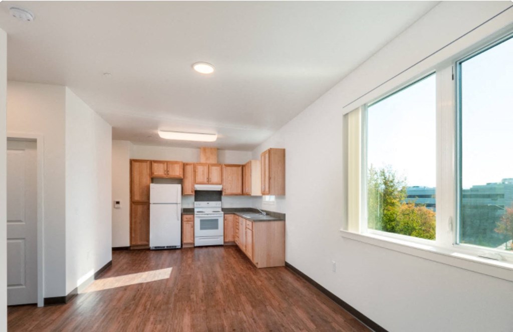 an empty kitchen with wooden cabinets and a large window
