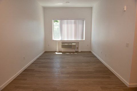 an empty room with wooden floors and a window