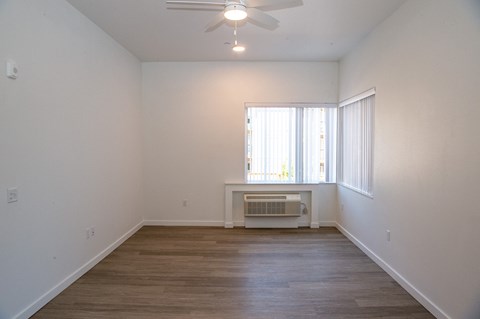 an empty living room with a ceiling fan and a window