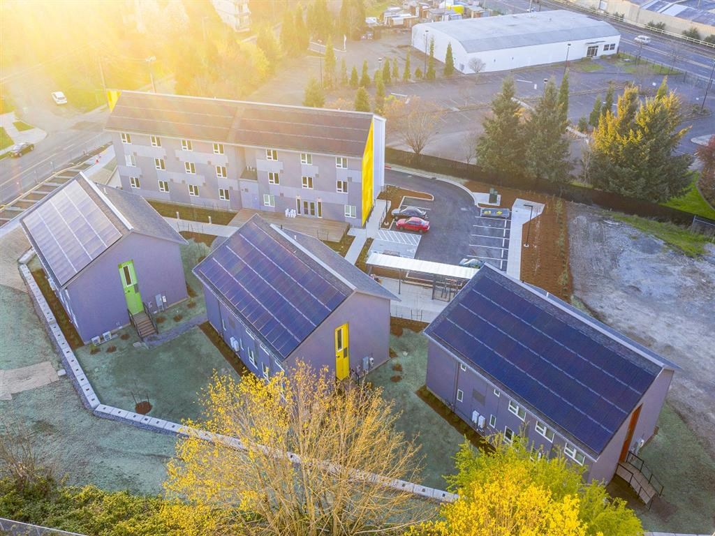 solar panels on the rooftops of three buildings and a parking lot