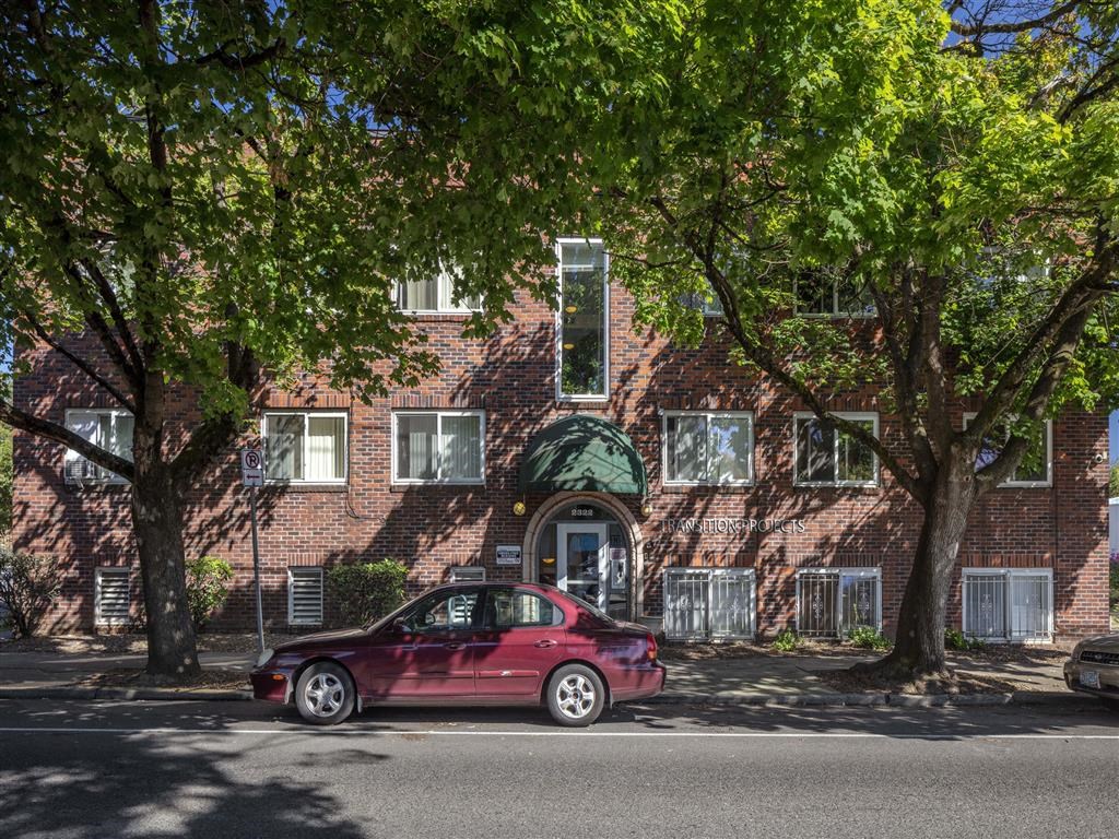 a red car parked in front of a brick house