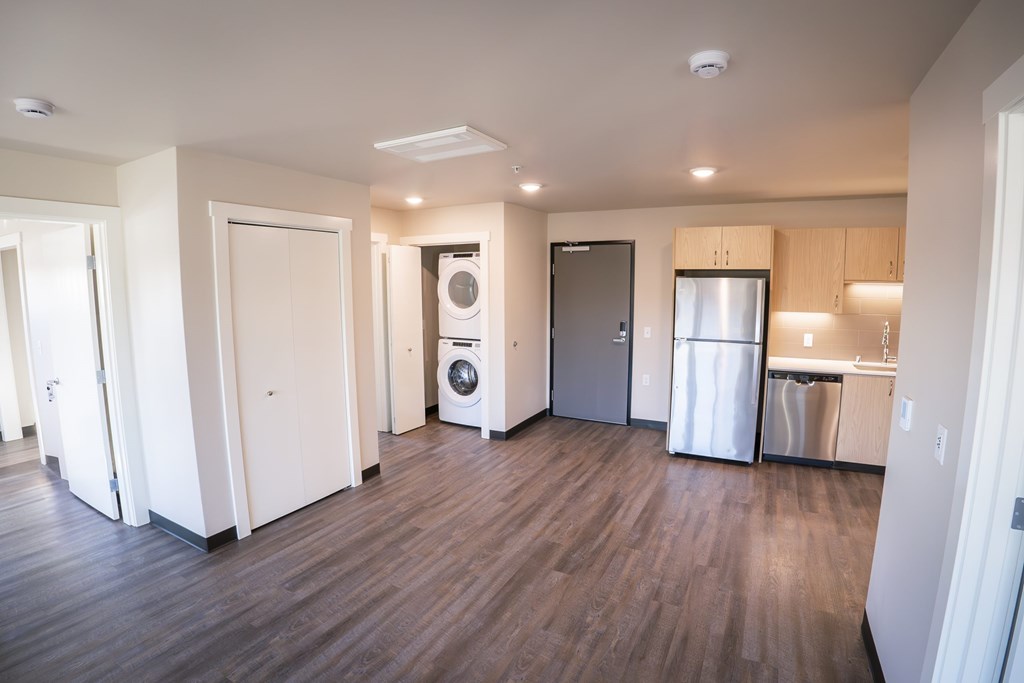 A kitchen area with a refrigerator, dishwasher, and washer.