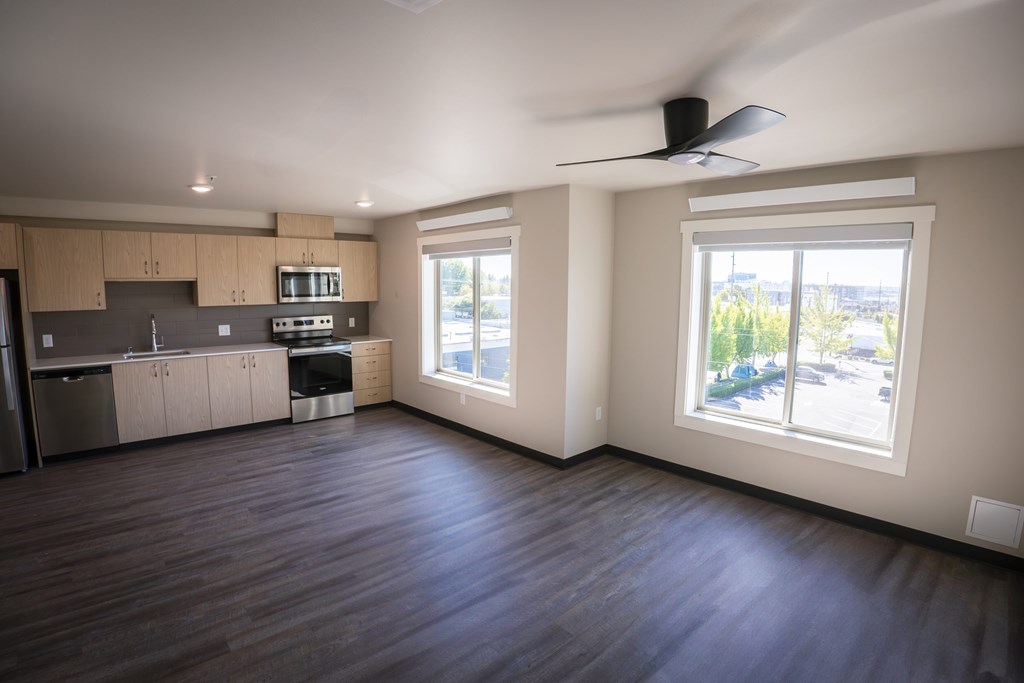 A spacious kitchen and living room with hardwood floors and large windows.