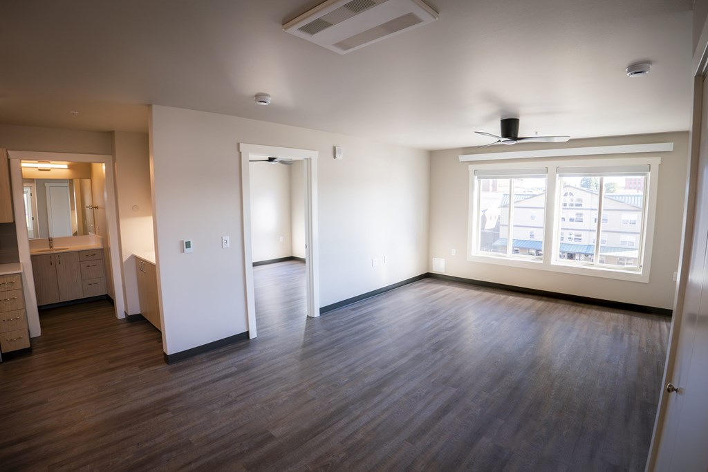 A room with wooden floors and a window with a view of buildings outside.