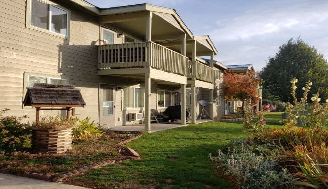 the back of a house with a porch and a lawn