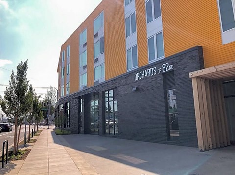 A modern building with the sign "Orchards of 82ND" on its facade.
