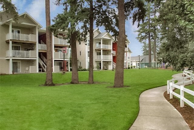 an exterior view of an apartment building with trees and a sidewalk