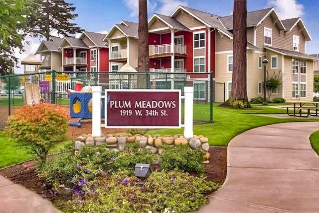 a sign for plum meadows in front of an apartment building