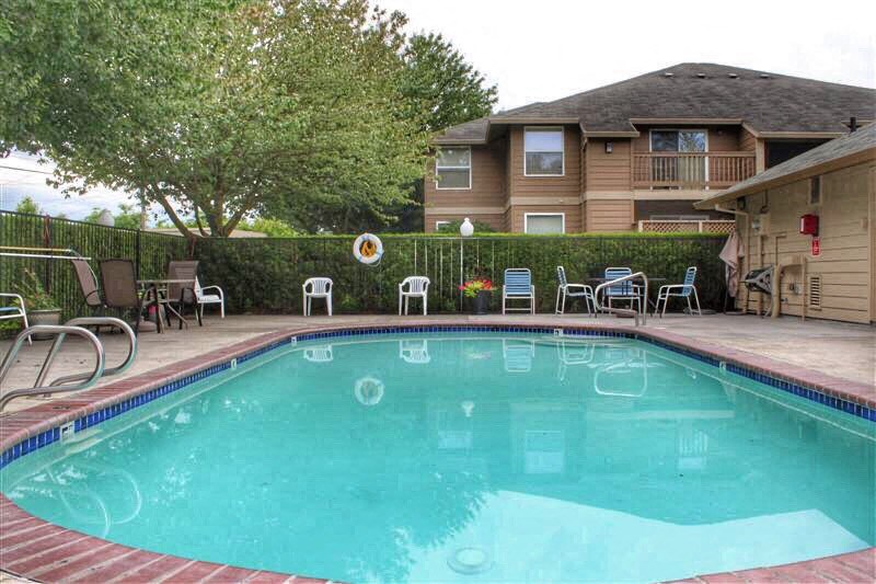 a swimming pool with chairs and a house in the background