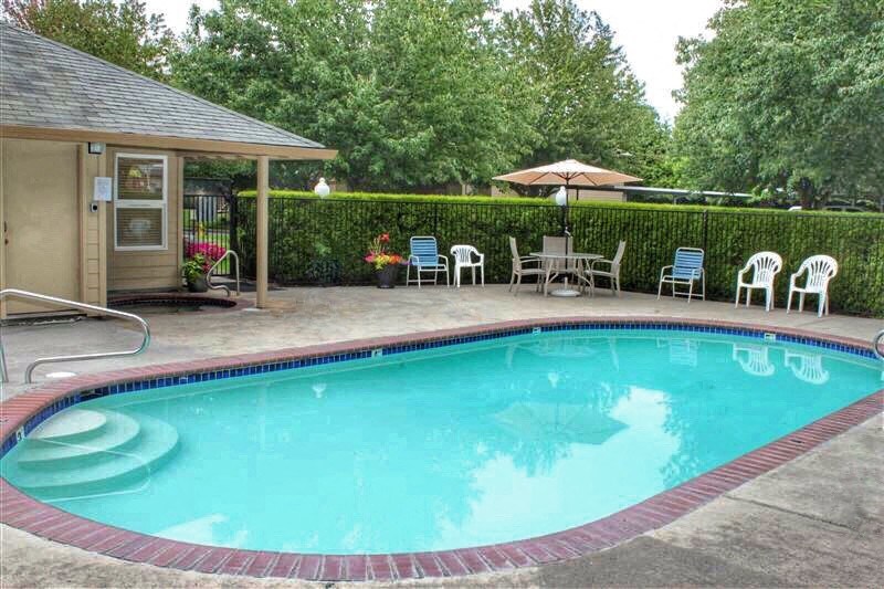 a swimming pool and a patio with chairs and an umbrella
