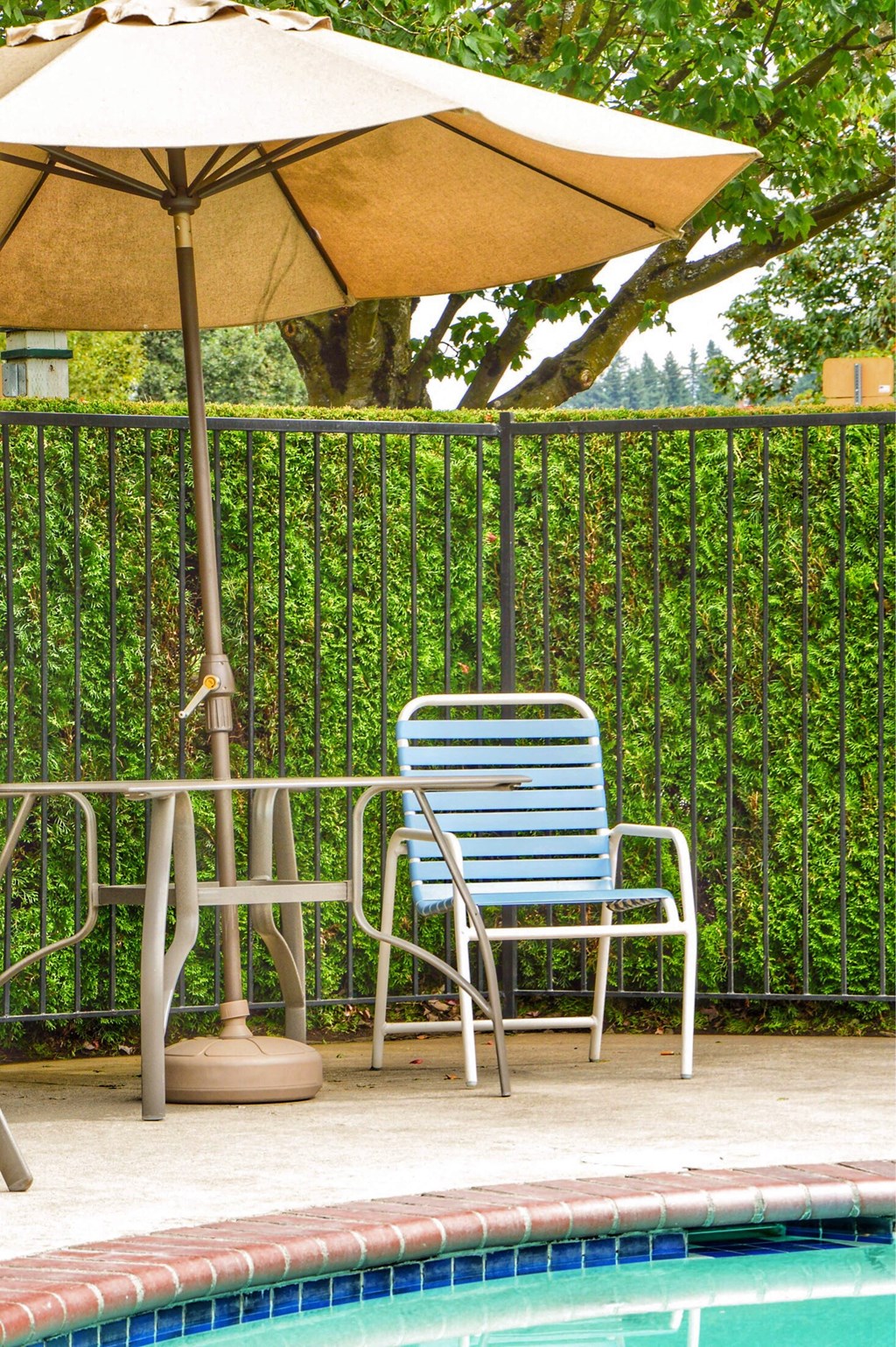 a chair and an umbrella next to a swimming pool