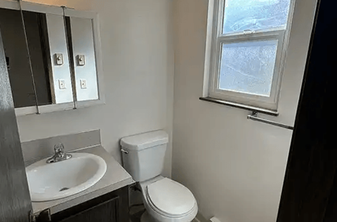 A bathroom with a toilet, sink, and mirror.