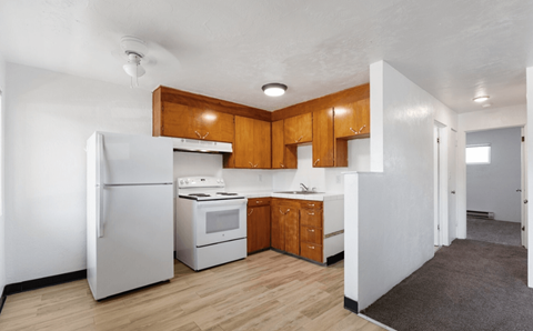 A kitchen with white appliances and wooden cabinets.