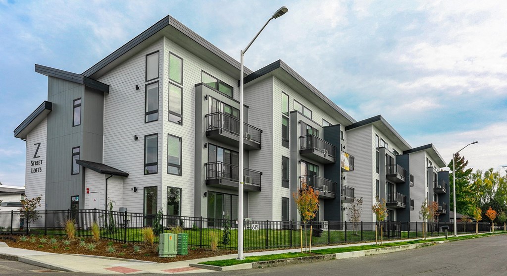 a row of townhomes with grey and green facades on a city street