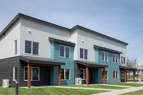 a blue and white house with a sidewalk and grass