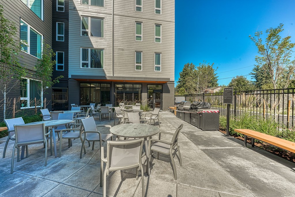 A patio with chairs and a table is in front of a building.