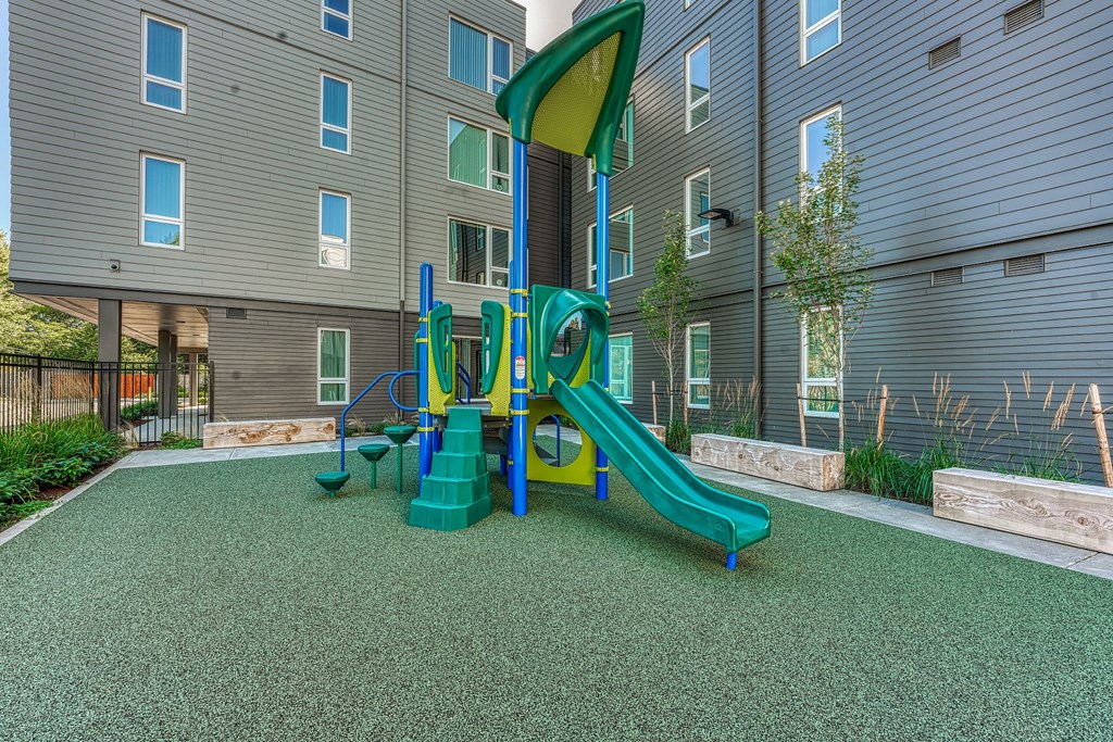 A playground with a green slide and a yellow and green play structure.
