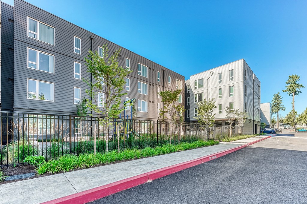 A street view of a residential area with modern buildings and a sidewalk.