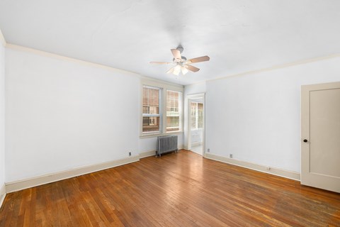 A room with a ceiling fan and wooden floors.