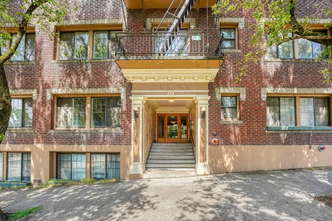 A red brick building with a balcony and a staircase leading to the entrance.
