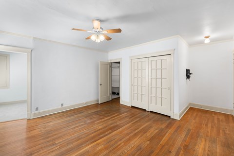 A room with a ceiling fan and wooden floors.