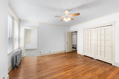 A room with a ceiling fan and wooden floors.