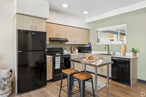 A modern kitchen with a black refrigerator and wooden cabinets.