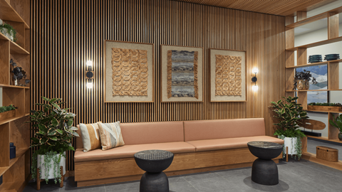 A living room with a couch, two tables, and a wooden wall.