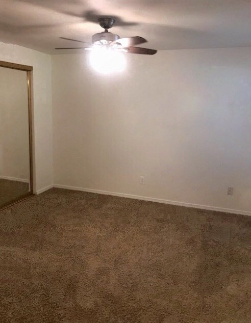 an empty room with a ceiling fan and a white wall