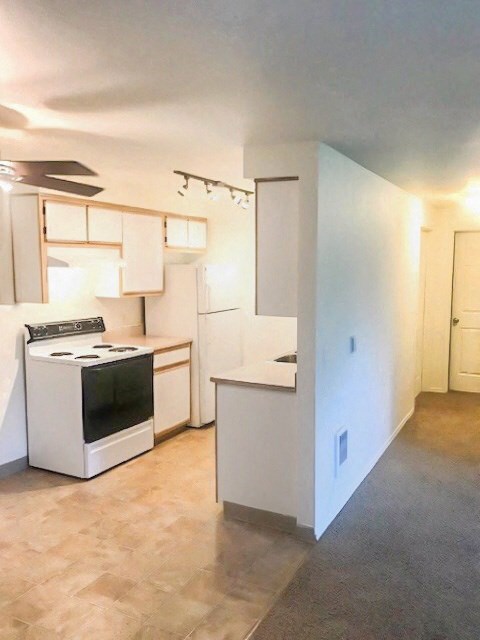 an empty kitchen with white cabinets and a stove