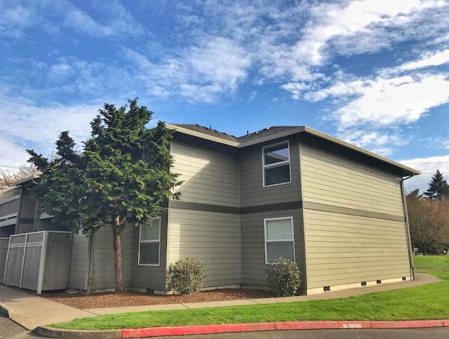a green house with a tree in front of it