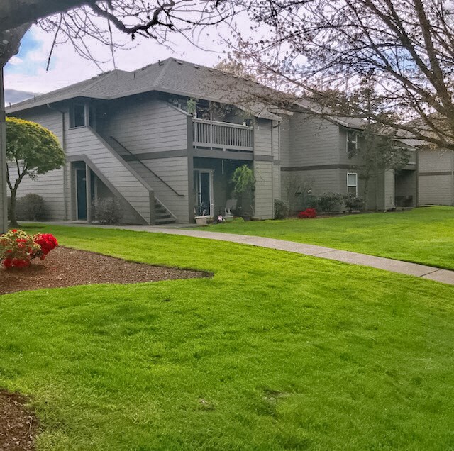 the front of a house with green grass and a sidewalk