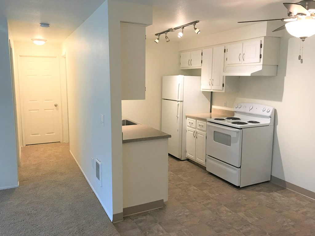 an empty kitchen with white appliances and white cabinets