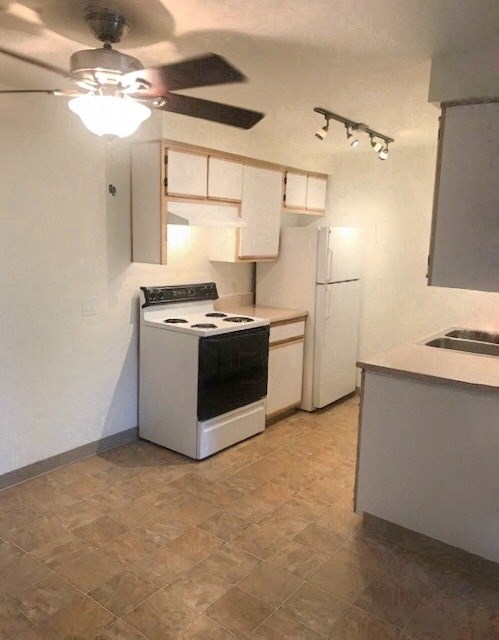 a kitchen with a stove and a ceiling fan