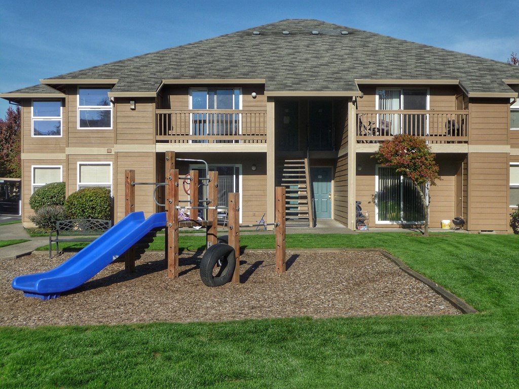 a playground in front of a house with a blue slide