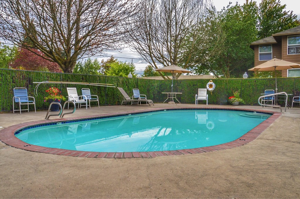 a swimming pool with chairs and umbrellas next to a house
