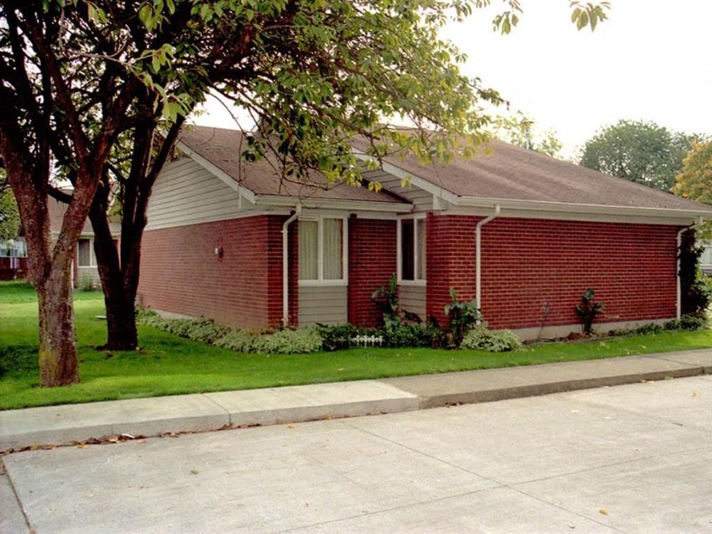 a red brick house with a tree in front of it