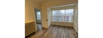 an empty living room with a radiator and a window