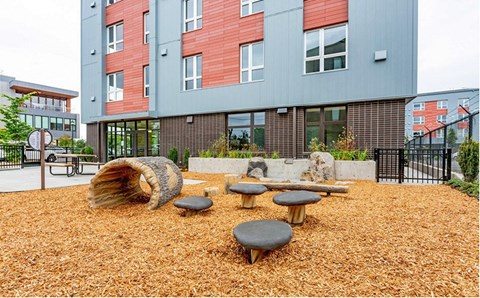 A playground area with a wooden log and several round tables.