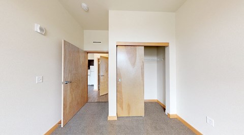 A room with a carpeted floor and two open doors.